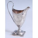 A George III silver helmet form pedestal cream jug, the ovoid body engraved with a foliate garland