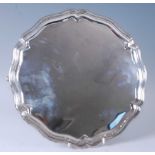 A George V silver salver, of shaped circular form with a raised stepped rim and plain ground,