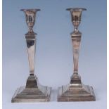 A pair of George V silver candlesticks, having pedestal urn sconces on square tapering columns to