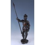 A bronze figure of a medieval knight modelled in standing pose with body armour and holding his