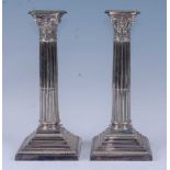 A pair of Edwardian silver plated Corinthian column candlesticks, each having embossed capitals