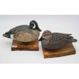 Two carved and painted wood models of ducks, each mounted upon a wooden plinth, signed and dated