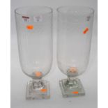 A pair of cut glass hurricane lamps, each upon a faceted stem and square stepped plinth, height