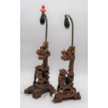 A pair of 20th century carved wood table lamps, each in the form of dogs of Fo before a tree, height