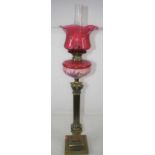 A Victorian pedestal oil lamp, having a cranberry tinted etched glass shade above a pink glass