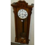 An early 20th century oak Vienna droptrunk wall clock, having a white enamel dial, pendulum, twin