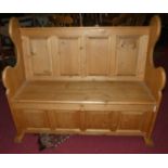 A contemporary pine four panelled settle, having fall front lower compartment, width 125cm