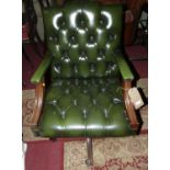 A reproduction mahogany, green leather buttoned and further studded open swivel desk chair, on