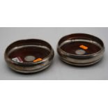 A pair of modern silver bottle coasters, each of squat circular form with mahogany base and silver
