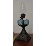A late Victorian oil lamp having a blue tinted glass font on pierced cast iron base, height 40cm (