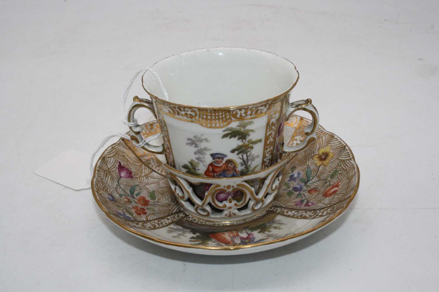 A 19th century Berlin porcelain trembleuse, the twin handled cup decorated with opposing reserves of