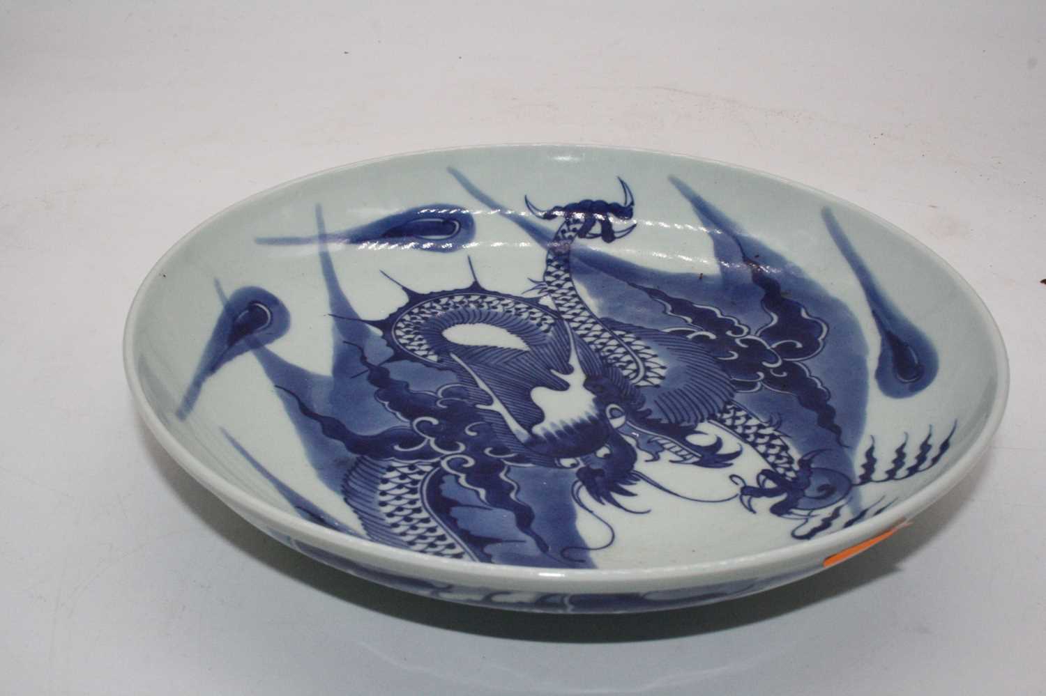 A Chinese export blue & white dish underglaze blue decorated with a four claw dragon chasing a