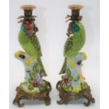 A pair of reproduction continental porcelain candlesticks each in the form of a parrot on gilt metal