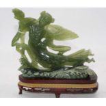 An eastern carved green hardstone figure, mounted upon a carved wooden stand, 26cm high