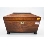 A Regency rosewood twin compartment tea caddy, of sarcophagus form, standing on four bun feet,