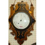 A Victorian aneroid wheel barometer, housed in a walnut and partial ebonised carved surround