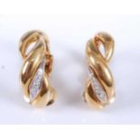 A pair of yellow metal diamond half hoop earrings, each featuring a two-strand twist design with