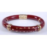 A yellow metal oval hinged hollow bangle, having red enamel inlay and star and crescent moon detail,