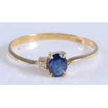 A yellow metal, sapphire and diamond two stone ring, featuring an oval faceted sapphire with a round