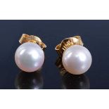 A pair of yellow metal cultured pearl stud earrings, each with a 7.3mm pearl and post and scroll