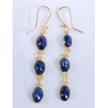 A pair of yellow metal sapphire drop earrings, each comprising three graduated oval faceted