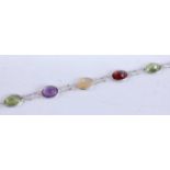 A white metal multi-stone bracelet, comprising 3 oval citrine, 3 oval garnet, 3 oval peridots and