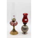 A late Victorian oil lamp, having a ruby tinted glass font, on a pierced brass foot; together with