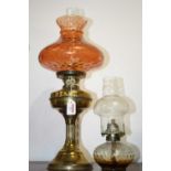 An early 20th century brass pedestal oil lamp, having an orange tinted glass shade; together with