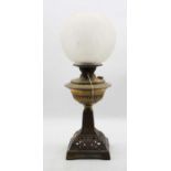 A Victorian oil lamp, having opalescent globular shade above a brass font, on a pierced iron base,