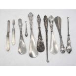 A collection of Victorian and later silver handled shoe-horns; together with silver handled button