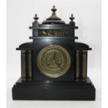 A late Victorian black slate cased mantel clock of architectural form, the circular brass dial