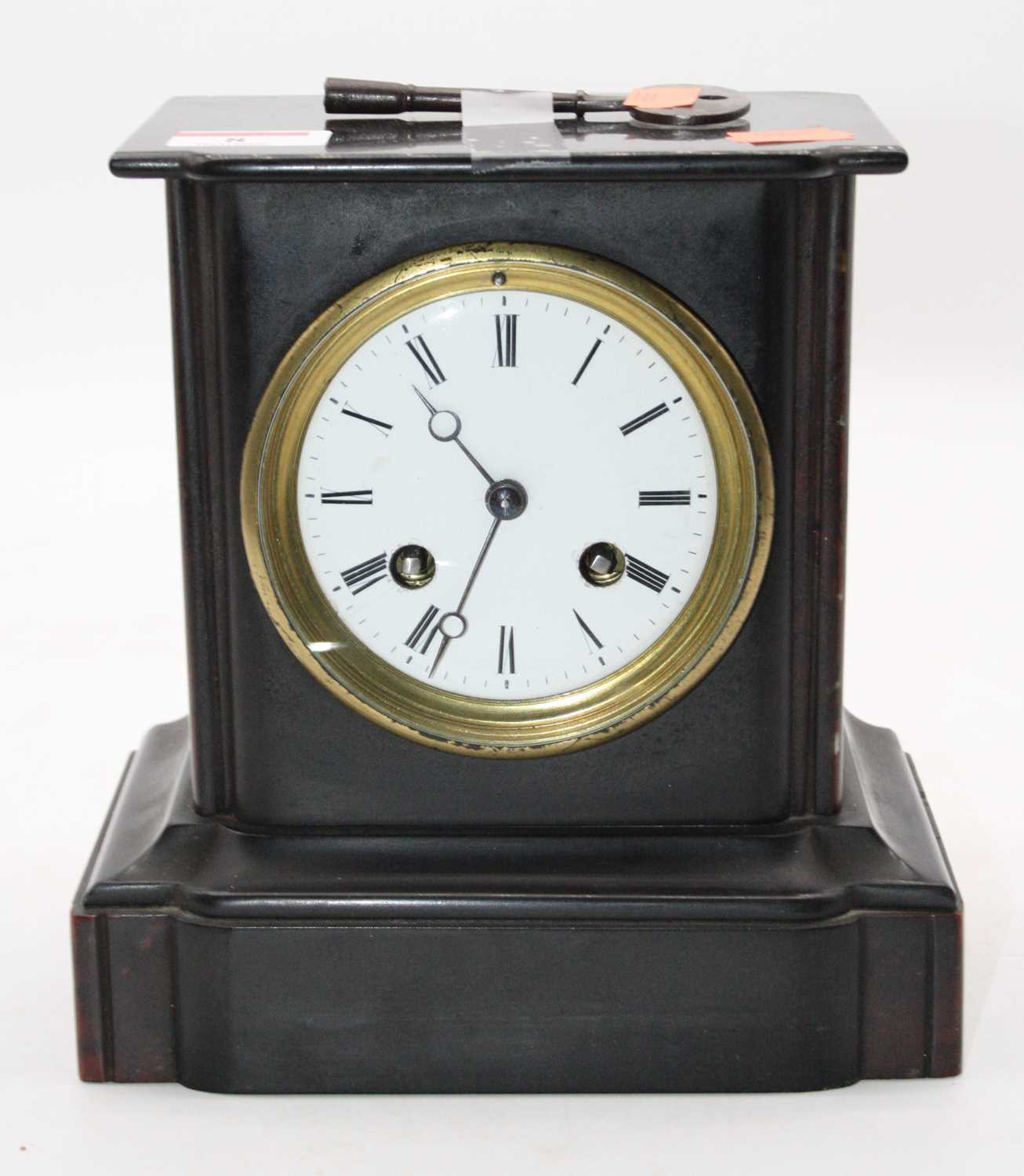 An Edwardian black slate cased mantel clock having a circular enamelled dial with Roman numerals and
