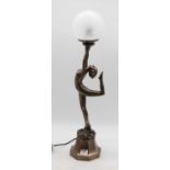 A reproduction Art Deco style table lamp, in the form of a female dancer holding a globular shade