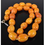 A beaded and knotted butterscotch amber single string necklace, 53.5g, the largest bead w.20mm,