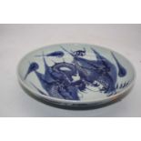 A Chinese export blue & white dish underglaze blue decorated with a four claw dragon chasing a