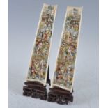 A pair of late 19th century ivory wrist rests, each intricately carved and polychrome painted with