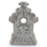 A large ornately carved stone clock case, the circular central aperture flanked by two mythical