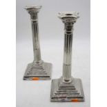 A pair of silver plated table candlesticks, each in the form of a Corinthian column upon a stepped
