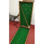 An early 20th century mahogany fold-over table bagatelle board, having baize lined interior (one cue