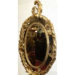 A large decorative contemporary French style floral decorated oval wall mirror, having crested