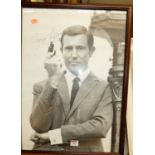 A monochrome photographic promotional print of George Lazenby as 007 James Bond, 55 x 40cm