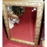 A reproduction framed and bevelled rectangular wall mirror, in a gilt composition leaf-moulded