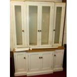 A contemporary white painted breakfront bookcase cupboard, having four glazed upper doors over