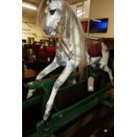 A child's dapple grey rocking horse, having leather studded saddle, raised on a green painted stand,
