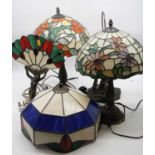 A pair of Tiffany style table lamps, each having domed leaded glazed shade on fluted column and