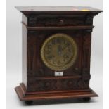 A late 19th century continental oak cased mantel clock having a brass dial with Arabic numerals