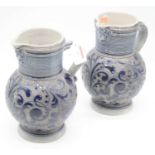 A pair of late 19th century German stoneware jugs each having a mask spout with banded neck, loop