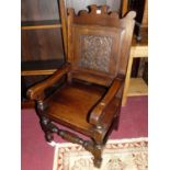 A contemporary oak floral carved, panelled back and seat Wainscot chair, raised on turned and square