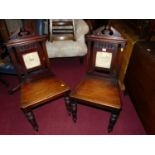 A pair of Victorian mahogany panelled seat hall chairs, each having ceramic inset and raised on ring