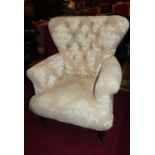 A contemporary cream floral buttoned upholstered scroll armchair, raised on turned forelegs to